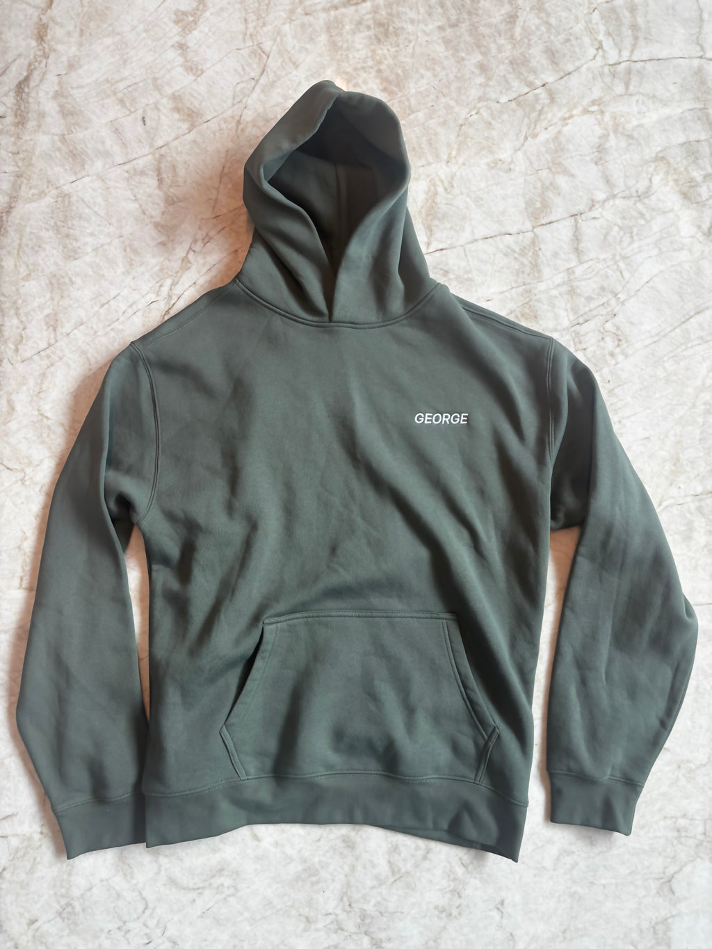 Green hoodie with 'George' logo on a textured surface